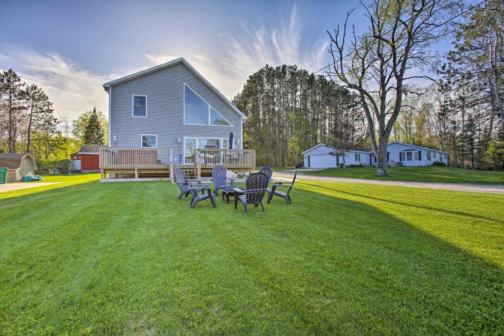 a group of chairs sitting on a lawn in front of a house at Home with Deck and Hot Tub - Lake Mitchell Views! in Cadillac