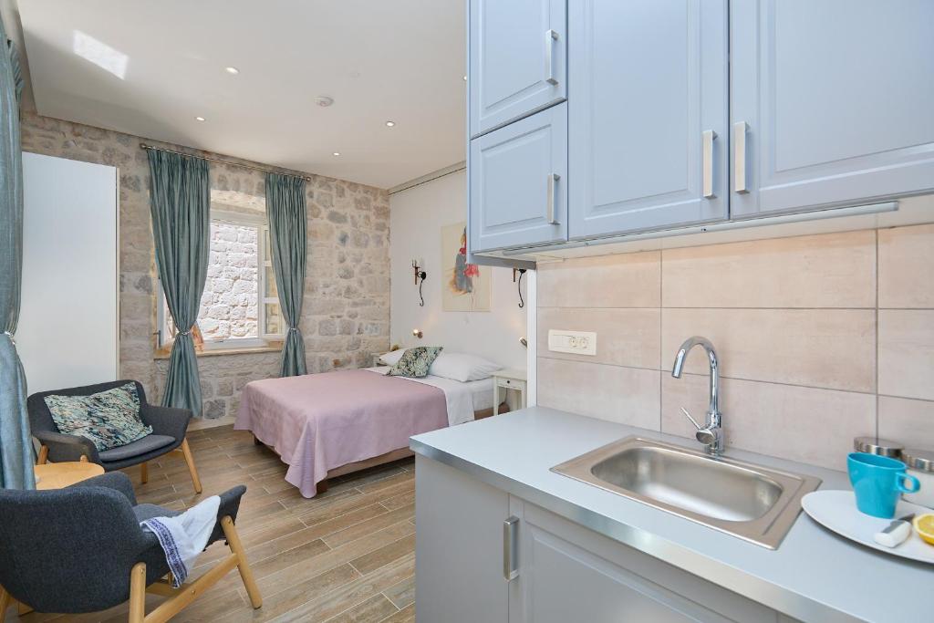een keuken met een wastafel en een kamer met een bed bij Studio Nikol in Dubrovnik