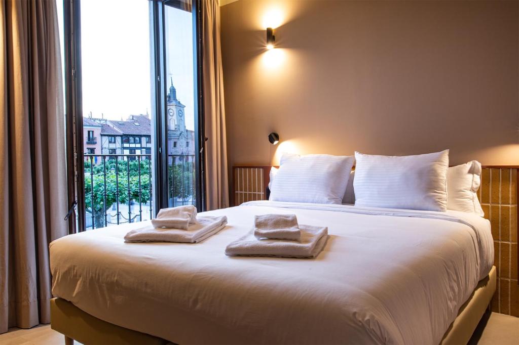 a bedroom with a large bed with towels on it at CASA Y FONDA 1888 in Alcalá de Henares