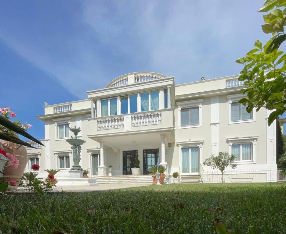 uma grande casa branca com uma estátua no quintal em Villa Bianca a pochi passi dal mare con giardino esclusivo em Livorno