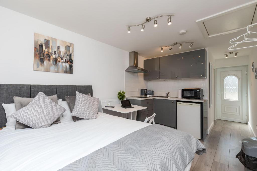 a bedroom with a large white bed and a kitchen at Findon- Stylish Suite 10mins close to Airport in Crawley