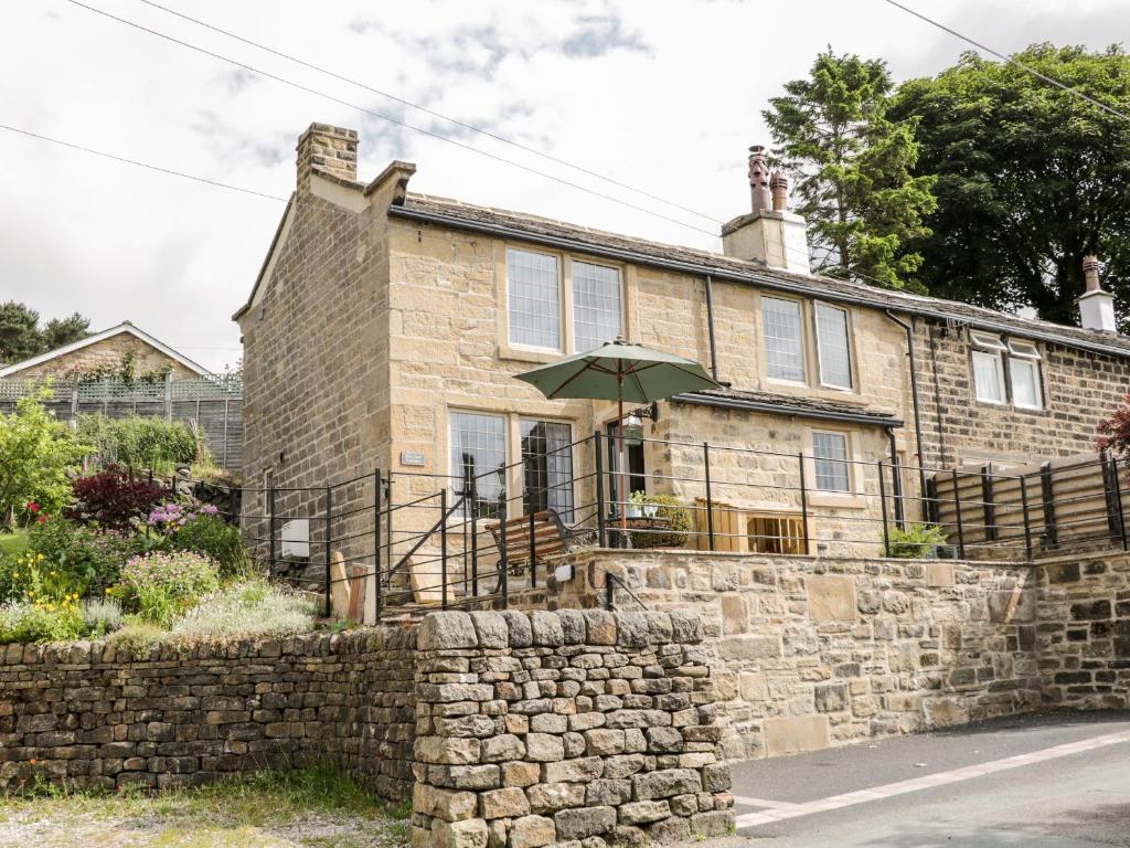 a brick house with an umbrella in front of it at Box Tree Cottage in Keighley