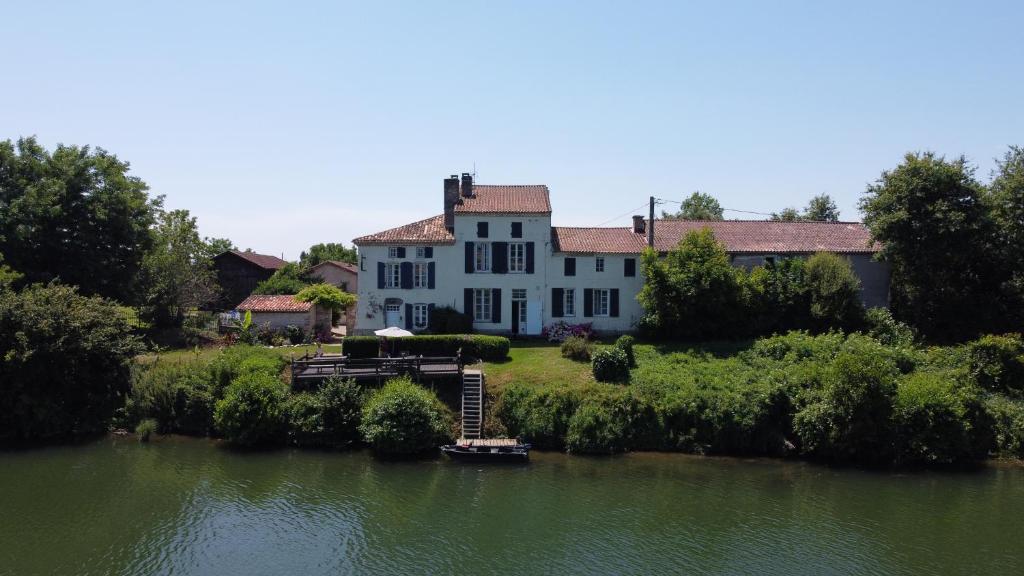 a large white house sitting on the side of a river at Les Séchoirs in Clairac