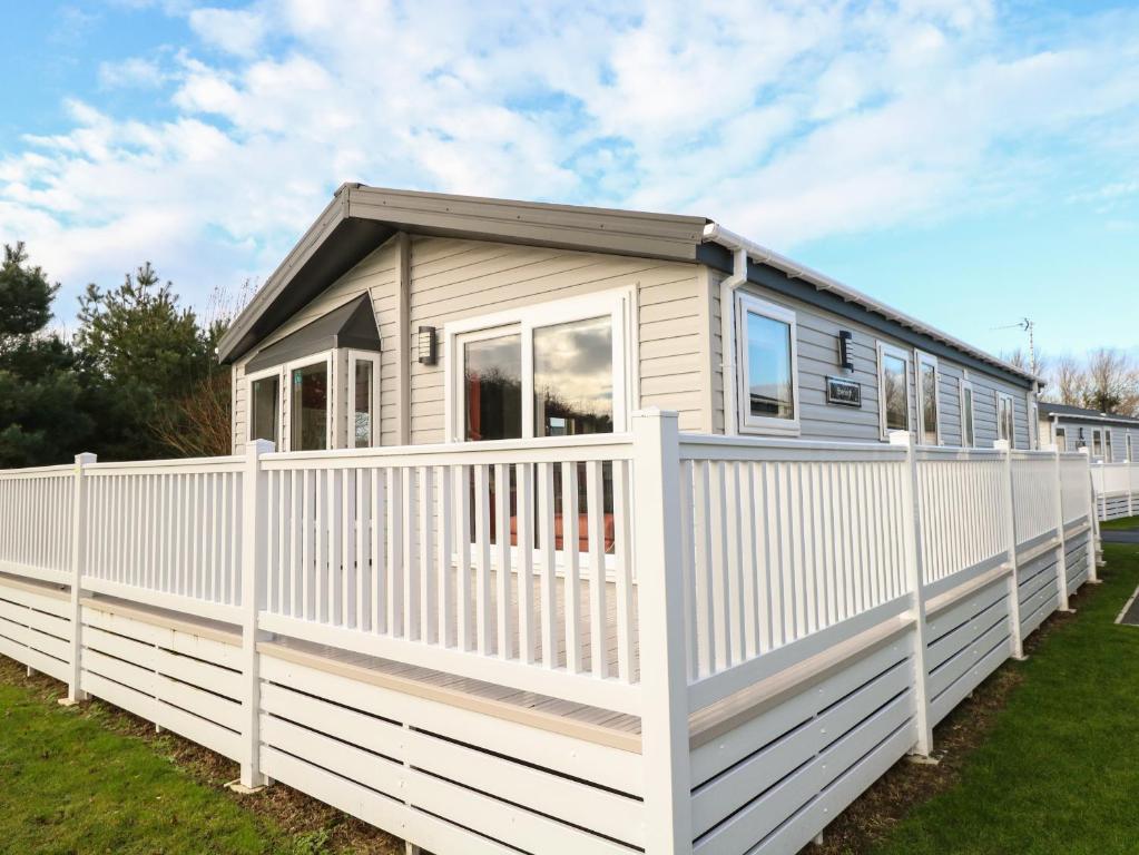 a tiny house with a white fence at Broadland Sands Lodge in Lowestoft