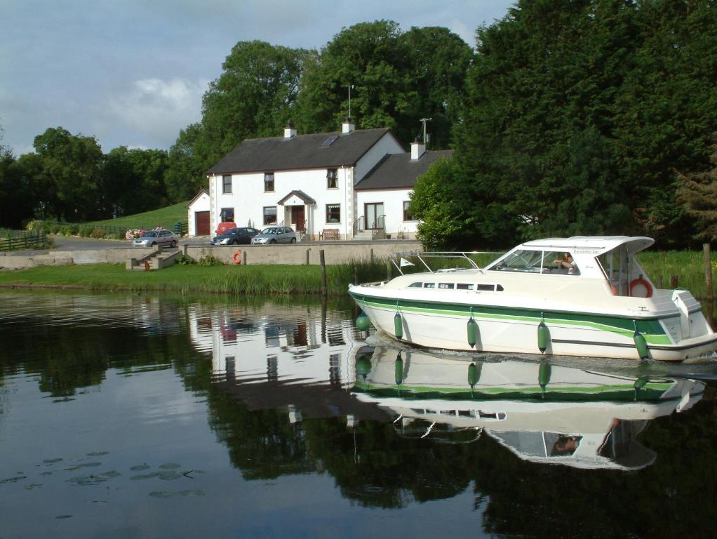 a boat sitting in the water in front of a house at Corrigans Shore House in Enniskillen