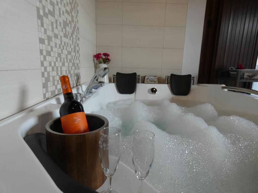 eine Flasche Wein und zwei Gläser in der Badewanne in der Unterkunft Lagar I con JACUZZI in Curiel de Duero