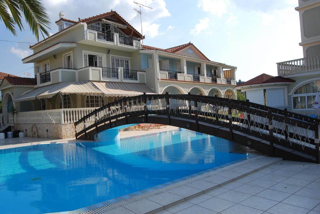 a bridge over a swimming pool in front of a building at Hotel Villa Basil in Tsilivi