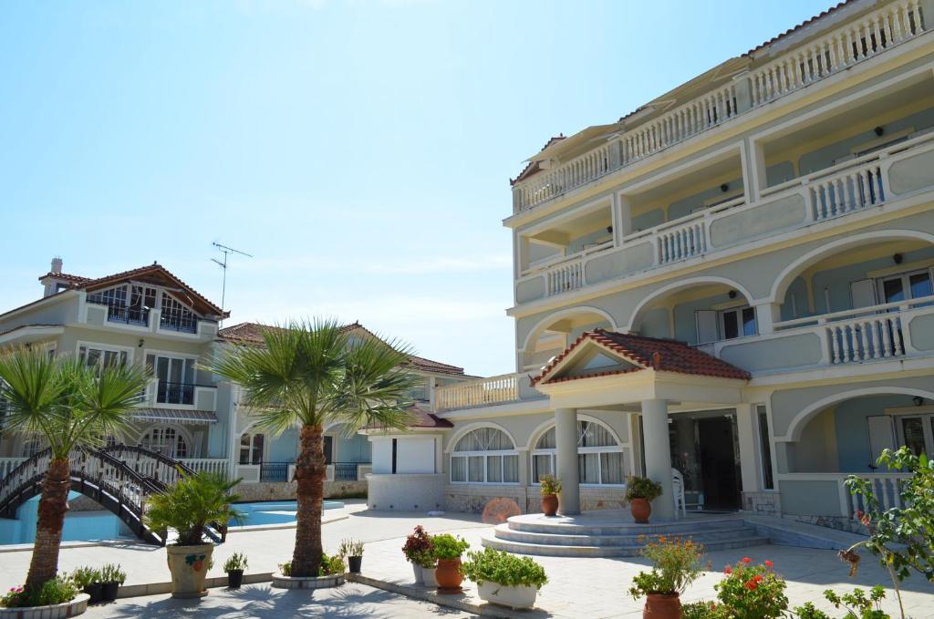 a large building with palm trees in front of it at Hotel Villa Basil in Tsilivi