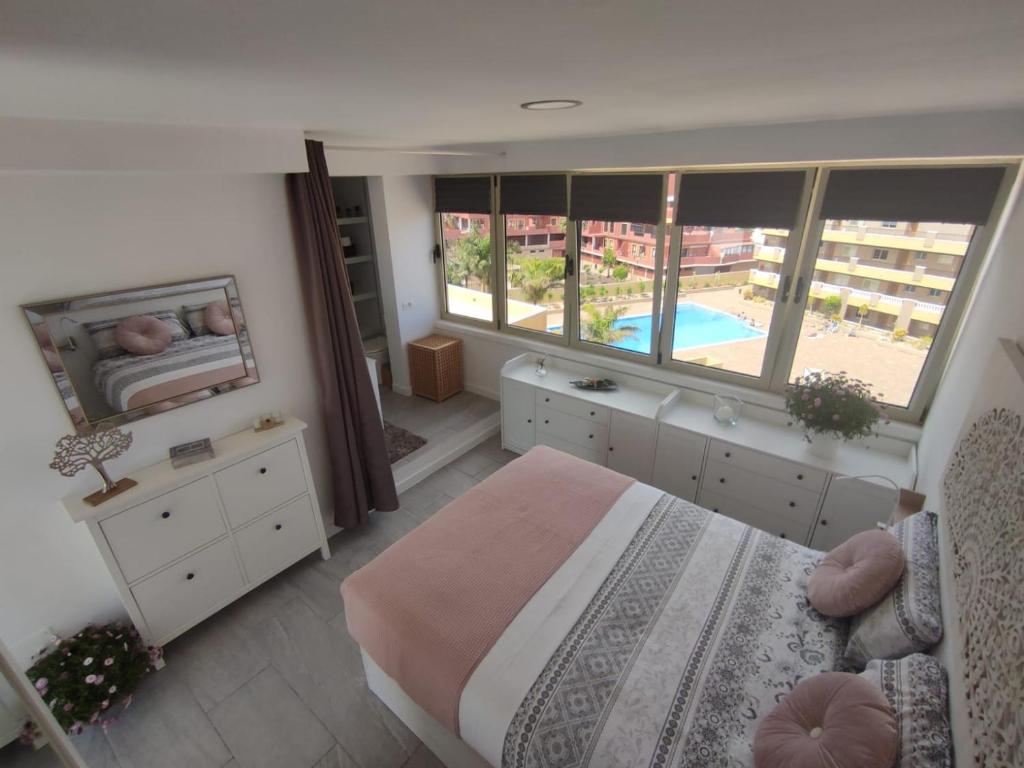 a bedroom with a bed and a view of a pool at Ático Orquídea in El Médano