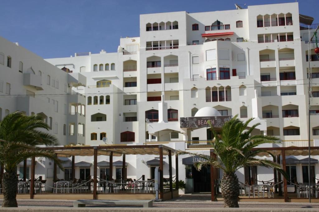 a large white building with palm trees in front of it at Atlantida by Garvetur in Quarteira