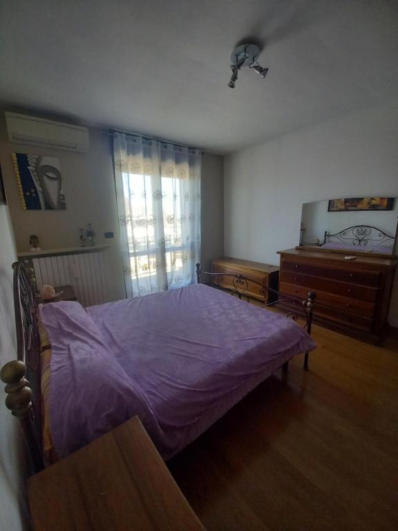 een slaapkamer met een bed met paarse lakens en een dressoir bij Camelia in Rivoli