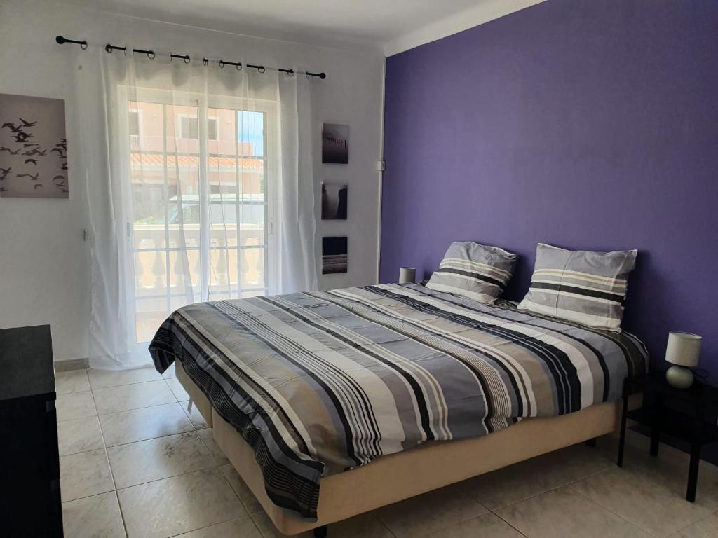 a bedroom with a bed with purple walls and a window at Brisa's Haven Guesthouse !Pet Friendly! in Lagos