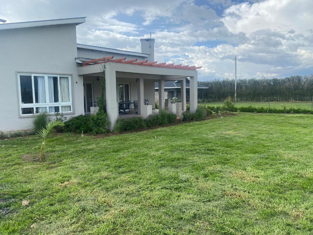 a white house with a lawn in front of it at Oloibor Farmhouse near Ol Pejeta Nanyuki in Nanyuki