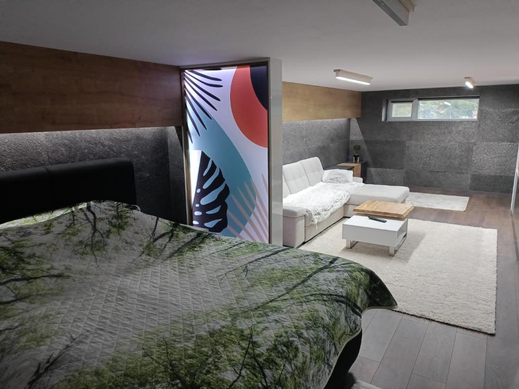 a bedroom with a bed and a living room at Újonnan épített, modern társasházi 2 szintes lakás in Topliţa-Ciuc