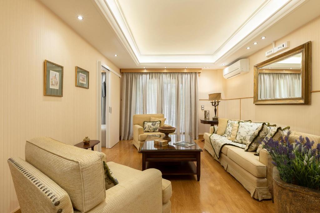 ein Wohnzimmer mit einem Sofa, Stühlen und einem Tisch in der Unterkunft Vouliagmeni's Elegance by Acropolis Suites in Athen