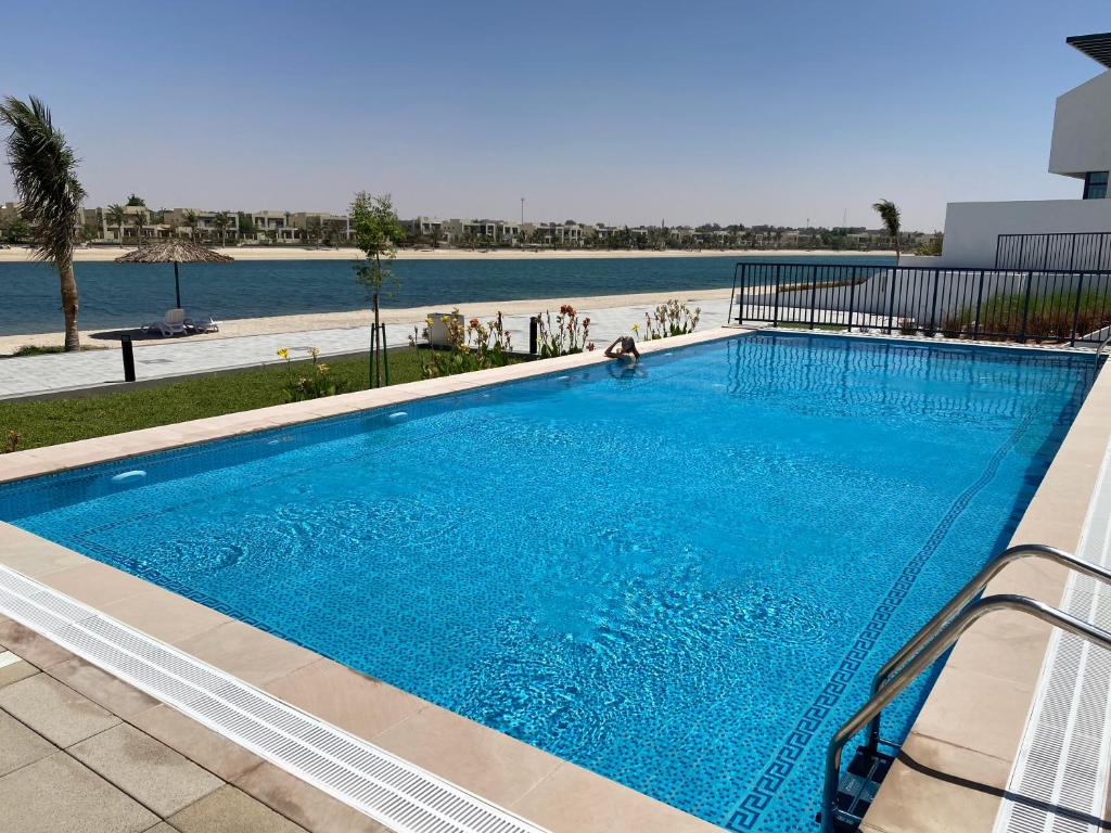 una gran piscina azul junto a un cuerpo de agua en Marbella Luxury 3BR & 5BR Villas at Hayat Island, Mina Al Arab, en Ras al Khaimah