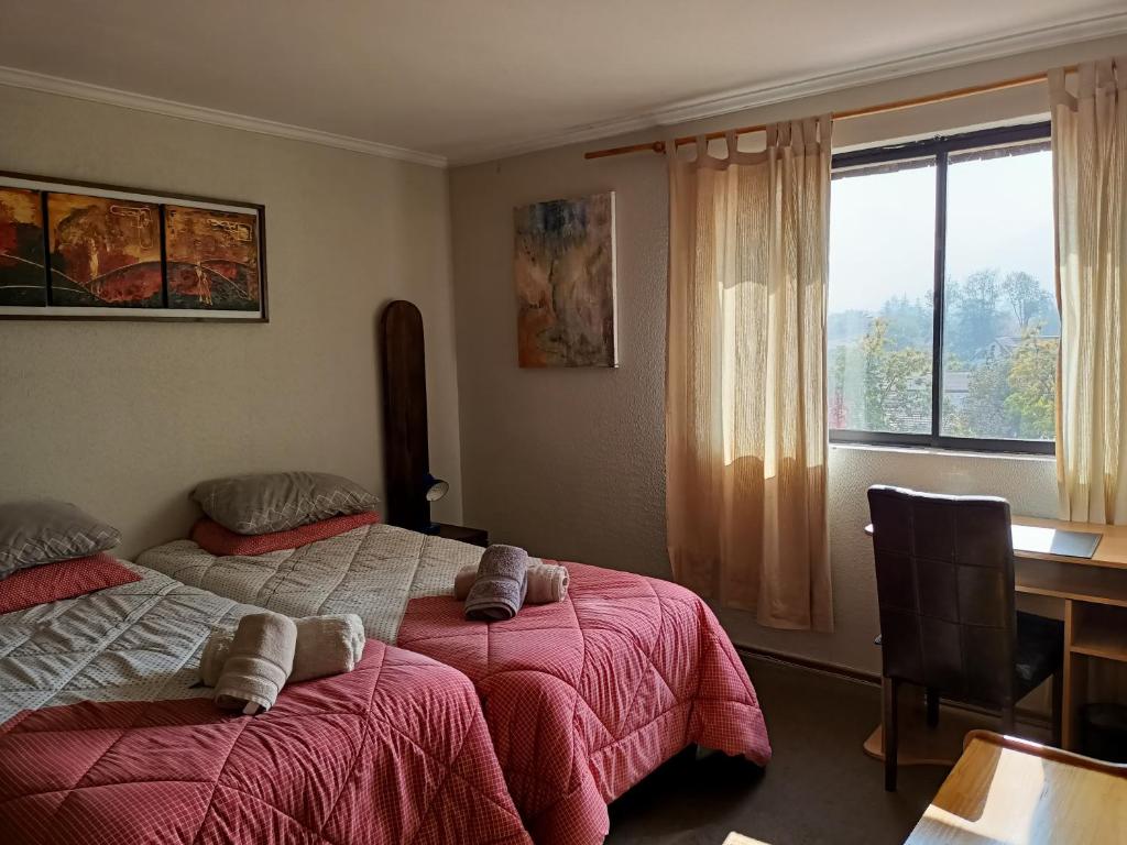 1 dormitorio con 2 camas, escritorio y ventana en Habitaciones en Departamento en Santiago