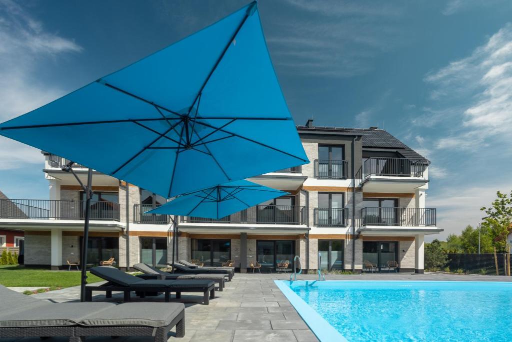 a pool with blue umbrellas in front of a building at Inny Klimat in Rowy
