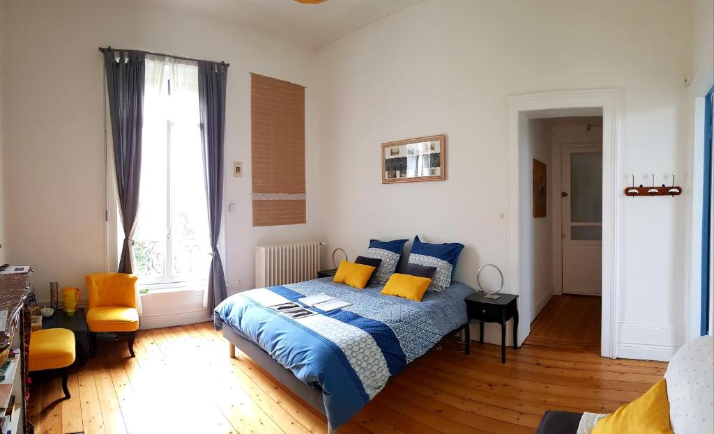 a bedroom with a bed with blue and yellow pillows at La maison des dentelliers in Calais