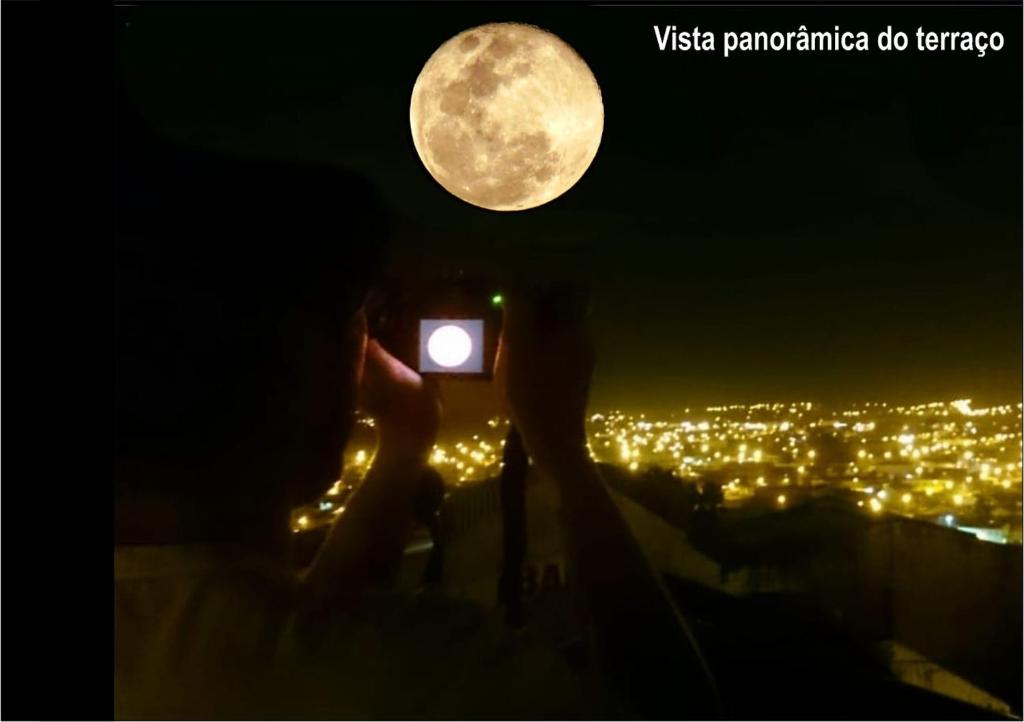 a person taking a picture of the moon at Mountain View in Curitiba