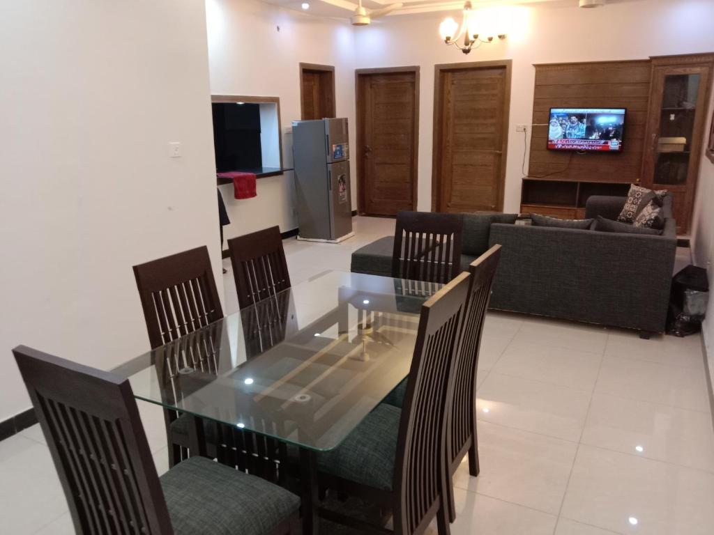 jadalnia i salon ze szklanym stołem i krzesłami w obiekcie Dream Villa w mieście Islamabad