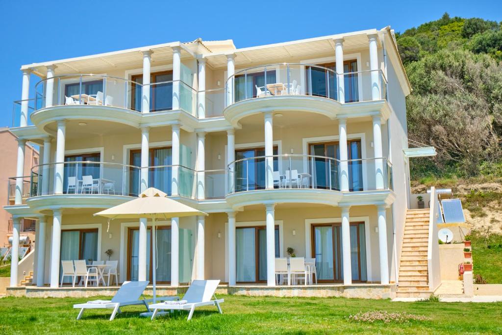 una grande casa bianca con sedie e ombrellone di Armikes Beachfront Suites Afionas a Afionas
