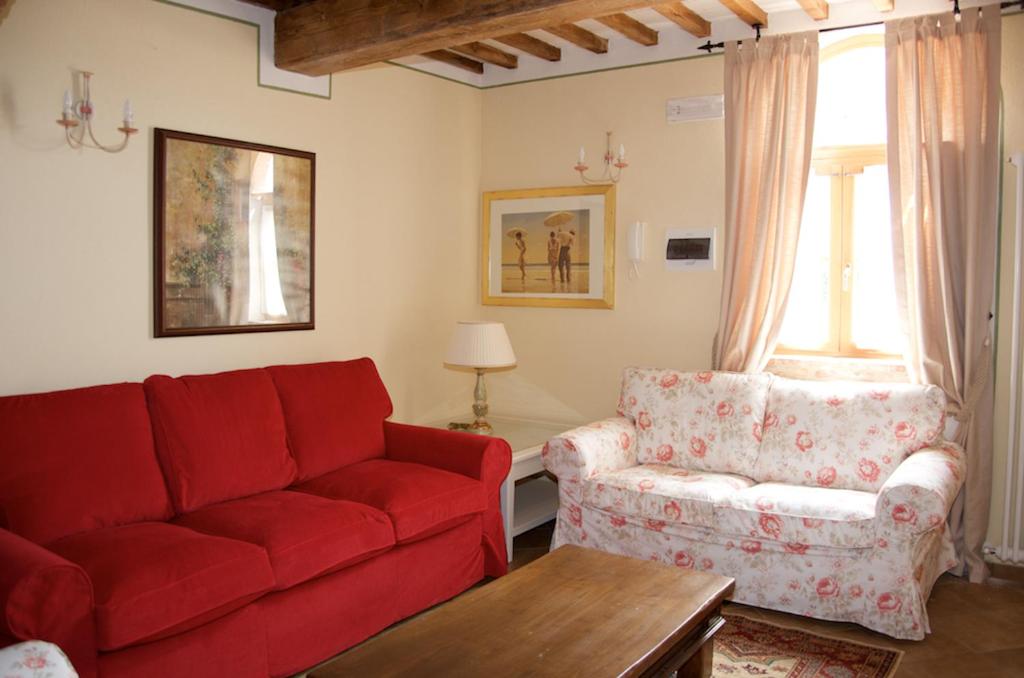 un soggiorno con divano rosso e sedia di Borgo 7 TigliAppartamento a Montepulciano n4 a Montepulciano