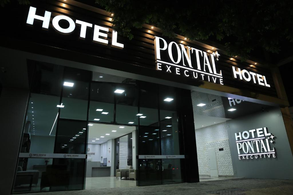 una señal de hotel frente a un edificio por la noche en Pontal Executive Hotel en Curvelo