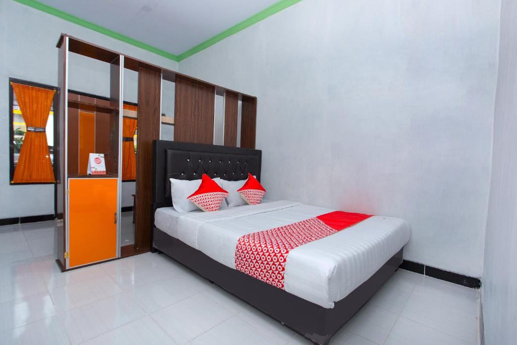 a bedroom with a bed with red and white pillows at SUPER OYO 2873 Griya Annisa in Tegal