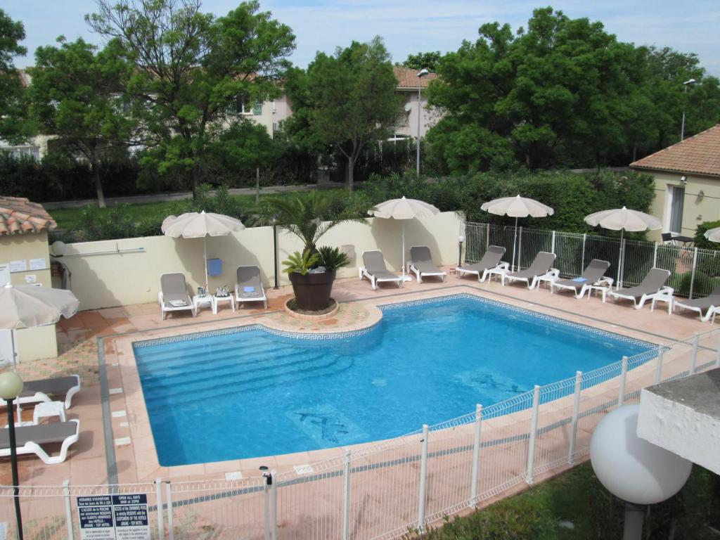 una gran piscina con sillas y sombrillas en Top Motel, en Istres