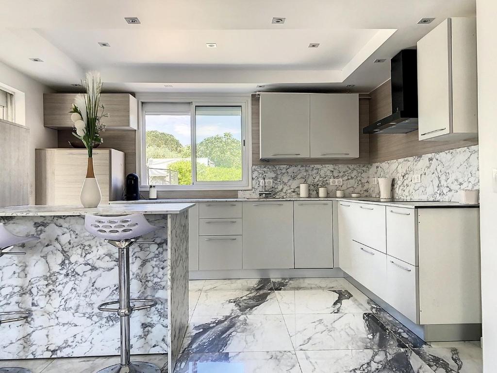 uma cozinha com armários brancos e piso em mármore em 3 Pièces climatisé en rez de jardin avec piscine em Villeneuve-Loubet