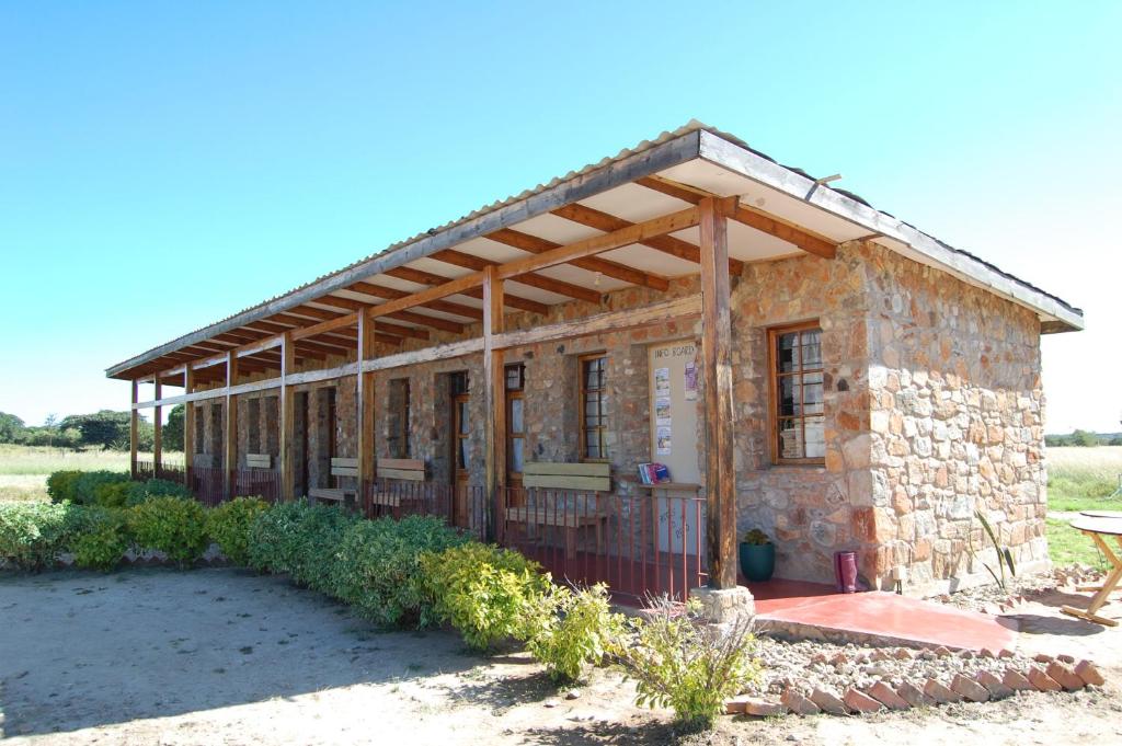 a small stone building with a wooden roof at MARK's farm & ecolodge in Kalenga