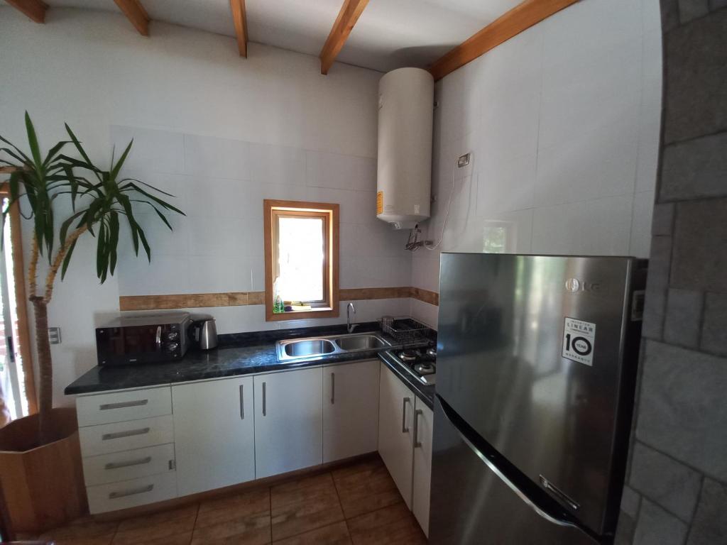 una cucina con frigorifero in acciaio inossidabile e lavandino di Cabañas Golem - Camino Termas de Chillán a Guangualí