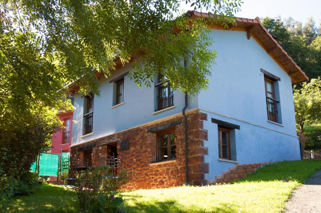 una casa de ladrillo y azul con un árbol en Casa La Pumarada de Villaviciosa, en Villaviciosa