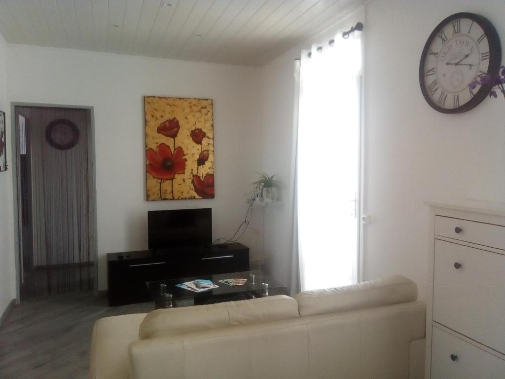 un salon avec un canapé et une horloge au mur dans l'établissement App. 6 couchages 3 chambres Stationnement gratuit, à Béziers