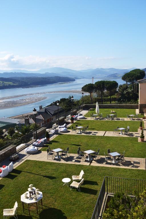 un parque con mesas de picnic y vistas al agua en Parador de Ribadeo, en Ribadeo