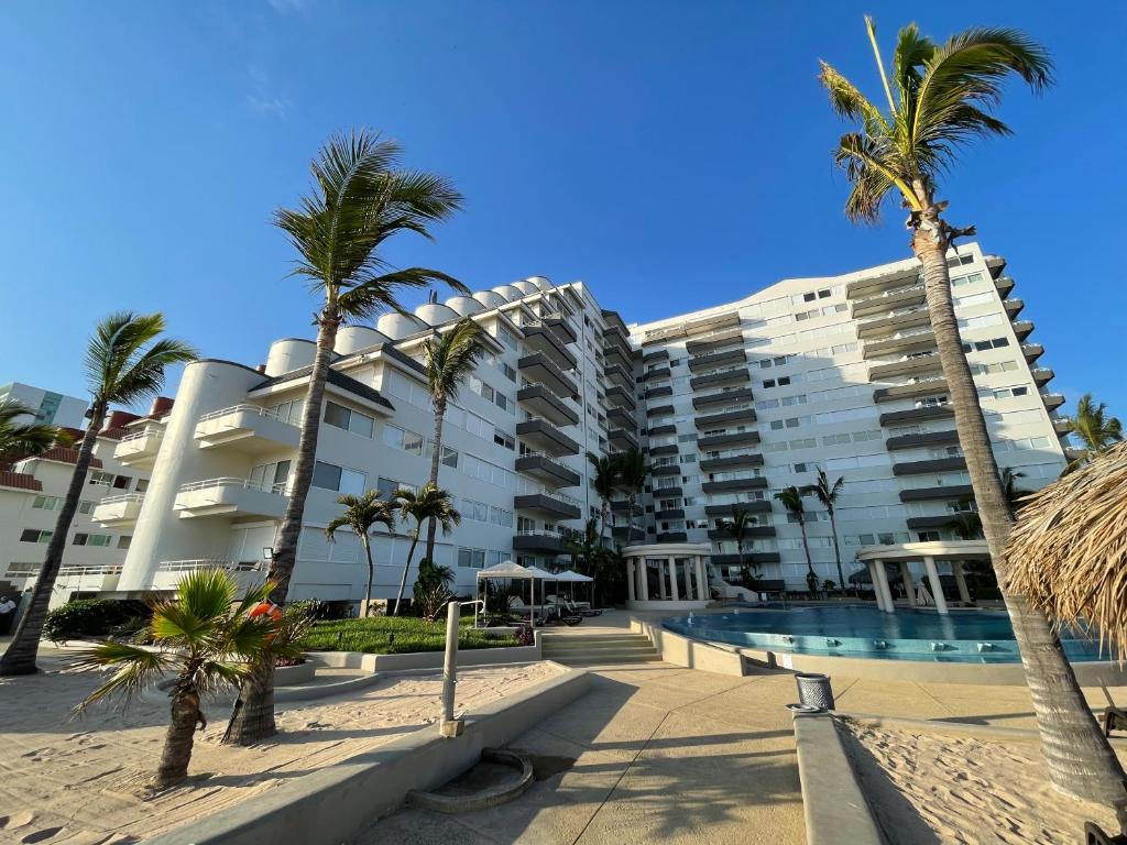 un complejo turístico con piscina y palmeras en a pie de playa con hermosa vista by G P S rentas, en Mazatlán