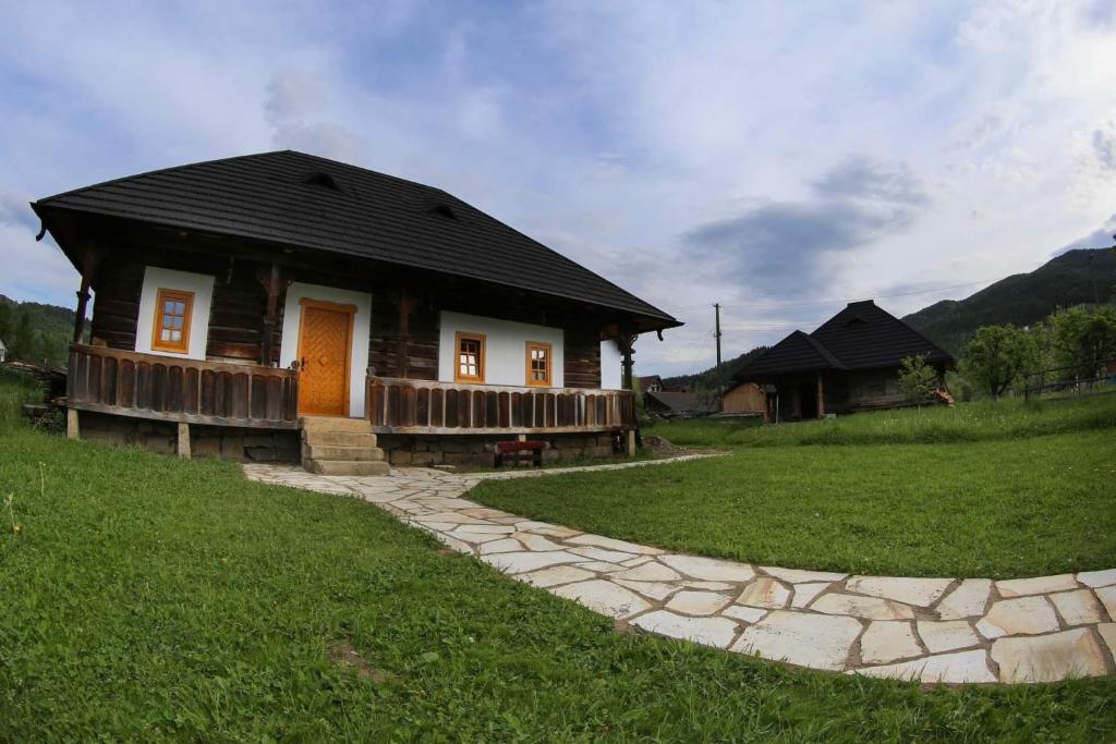 a small wooden house with a stone path leading to it at La căsuța cu amintiri in Vama