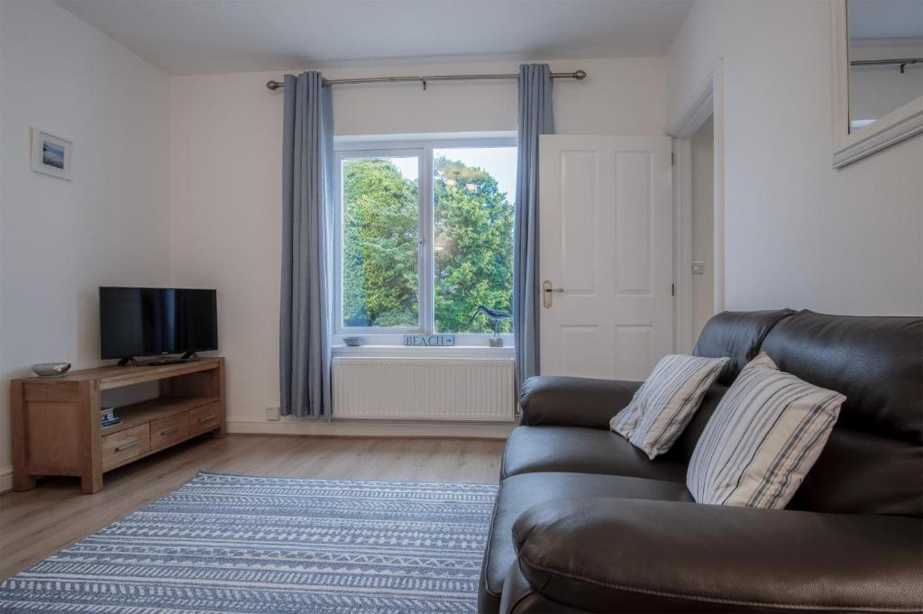 a living room with a couch and a television at Shorelands - 1 Bedroom Apartment - Manorbier in Manorbier