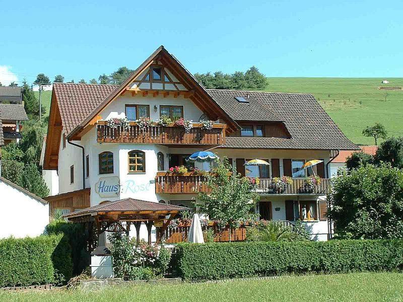 ein großes Haus mit einem Balkon mit Blumen darauf in der Unterkunft Pension Haus Rose in Oberharmersbach