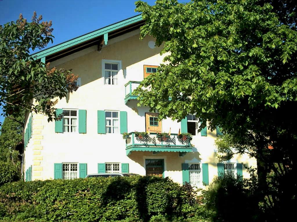 um grande edifício branco com janelas verdes e uma varanda em Ferienwohnung Spitzsteinblick em Sachrang