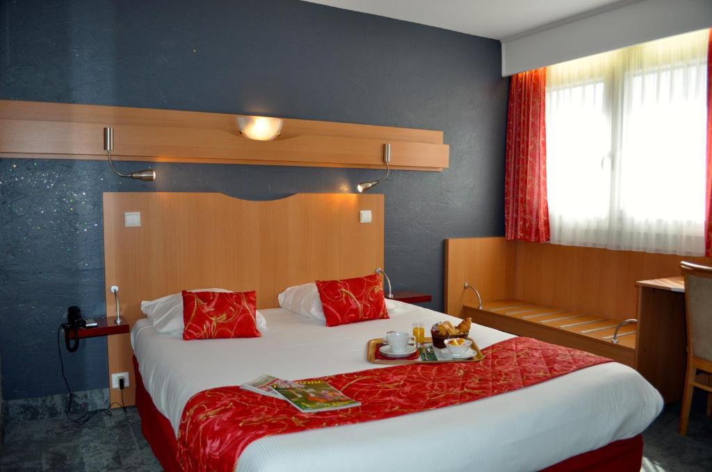 una habitación de hotel con una cama grande con almohadas rojas en Atalante, en Annemasse