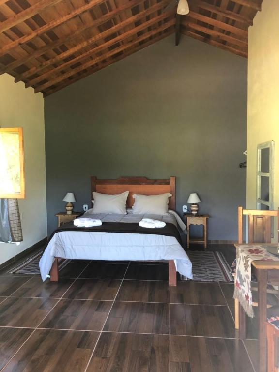 um quarto com uma cama e piso de madeira em Pousada Vale dos Sonhos em Cunha