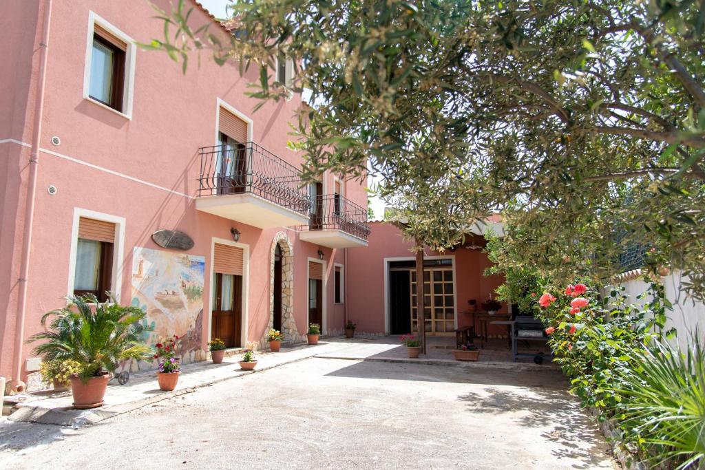 un bâtiment rose avec une cour en face dans l'établissement Baglio Mustazza, à Buseto Palizzolo