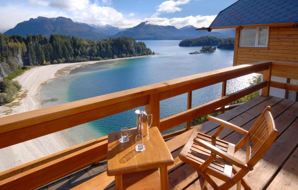 een tafel en stoelen op een terras met uitzicht op een meer bij Hostería Isla Victoria Lodge in Isla Victoria