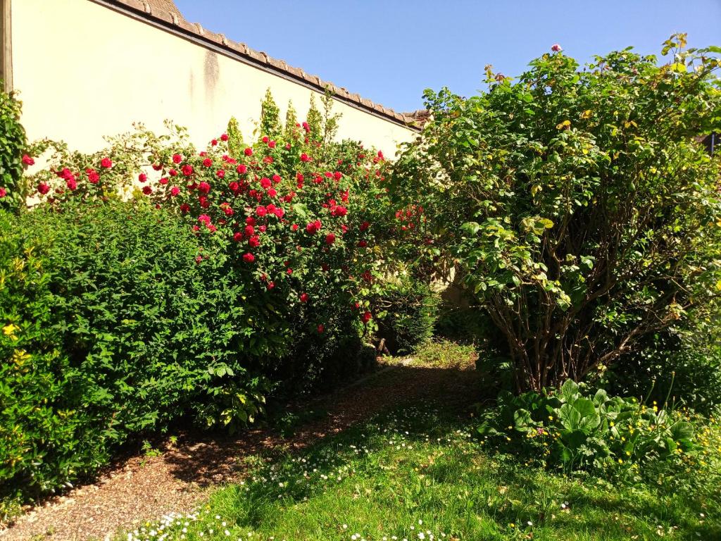 a garden with red flowers and bushes next to a building at L&#39;essentiel de Chartres in Chartres
