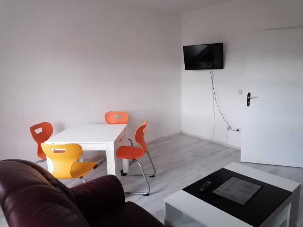 sala de estar con mesa blanca y sillas naranjas en Kunstgasse 11 Wohnung 8 en Altemburgo