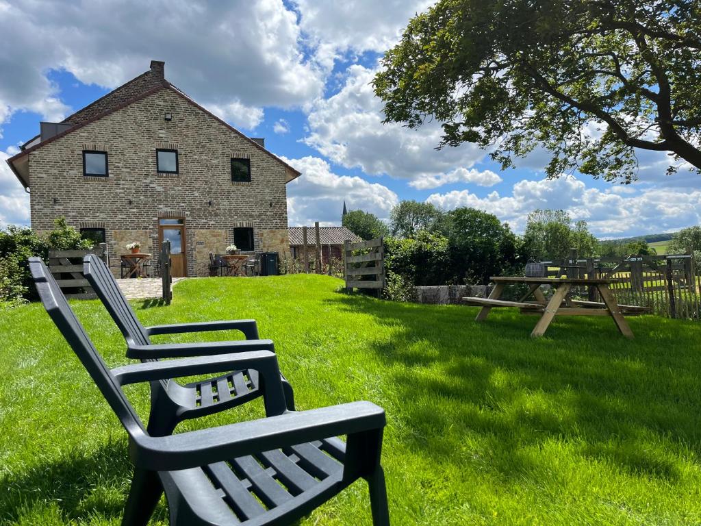 two lawn chairs sitting in the grass in front of a building at De Hoogstam in Vijlen