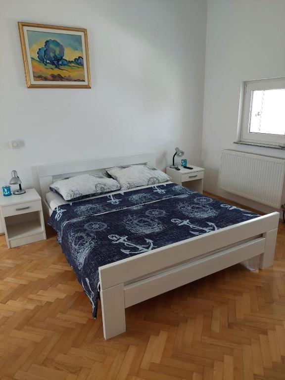 a bed in a white room with two tables at Apartments "Jope i Toni" in Biograd na Moru