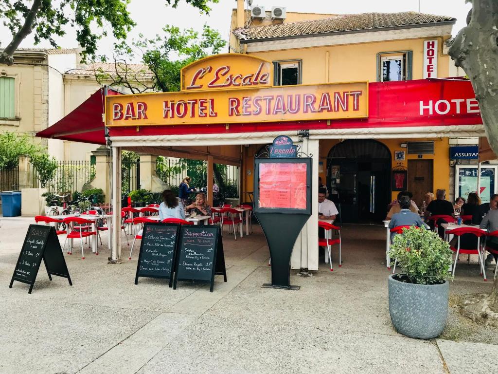 einem offenen Restaurant mit Tischen und Stühlen und einem Parkuhr in der Unterkunft Hotel L'Escale in Aigues-Mortes
